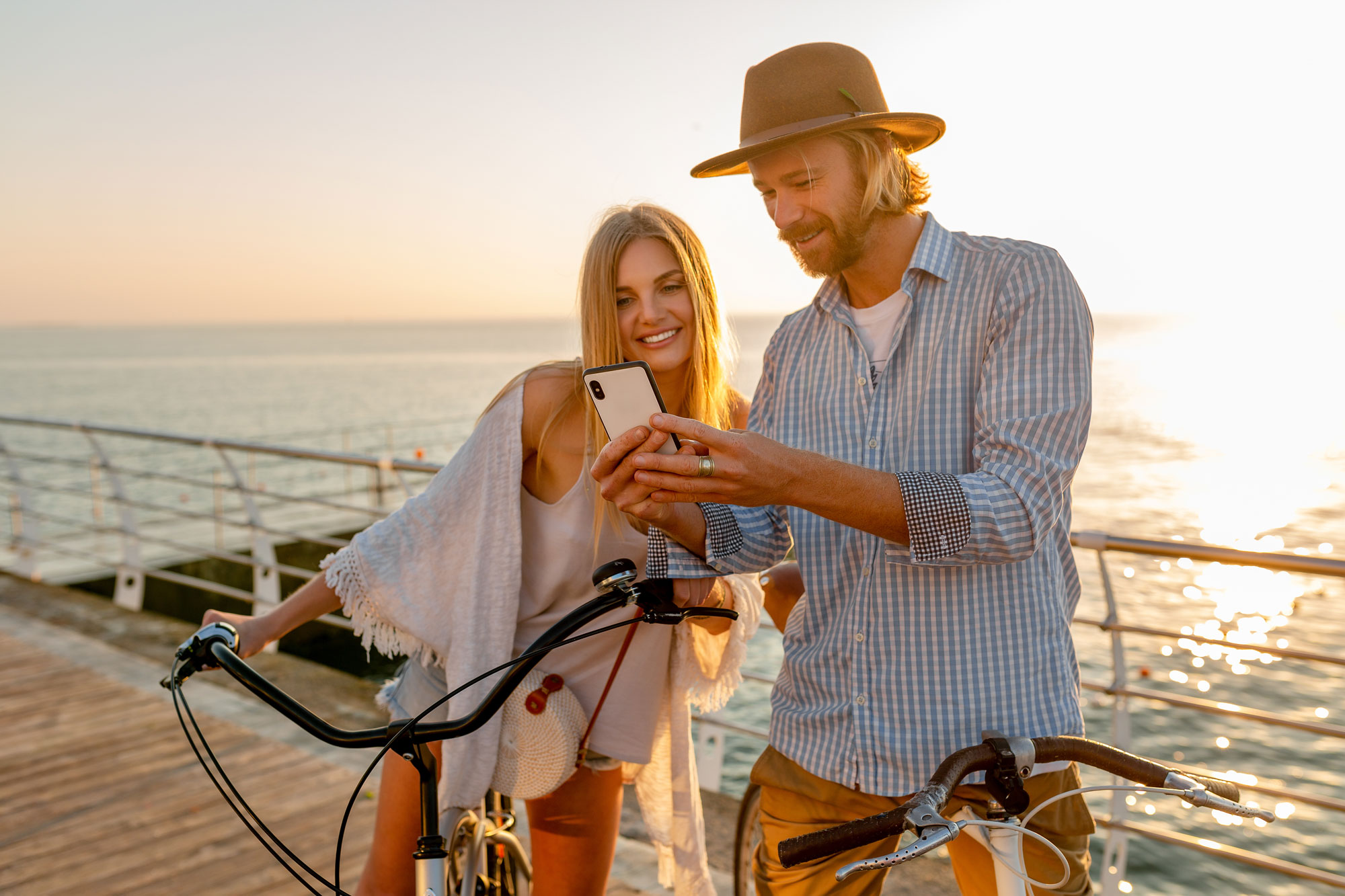 Una coppia in vacanza consulta lo smartphone vicino al mare